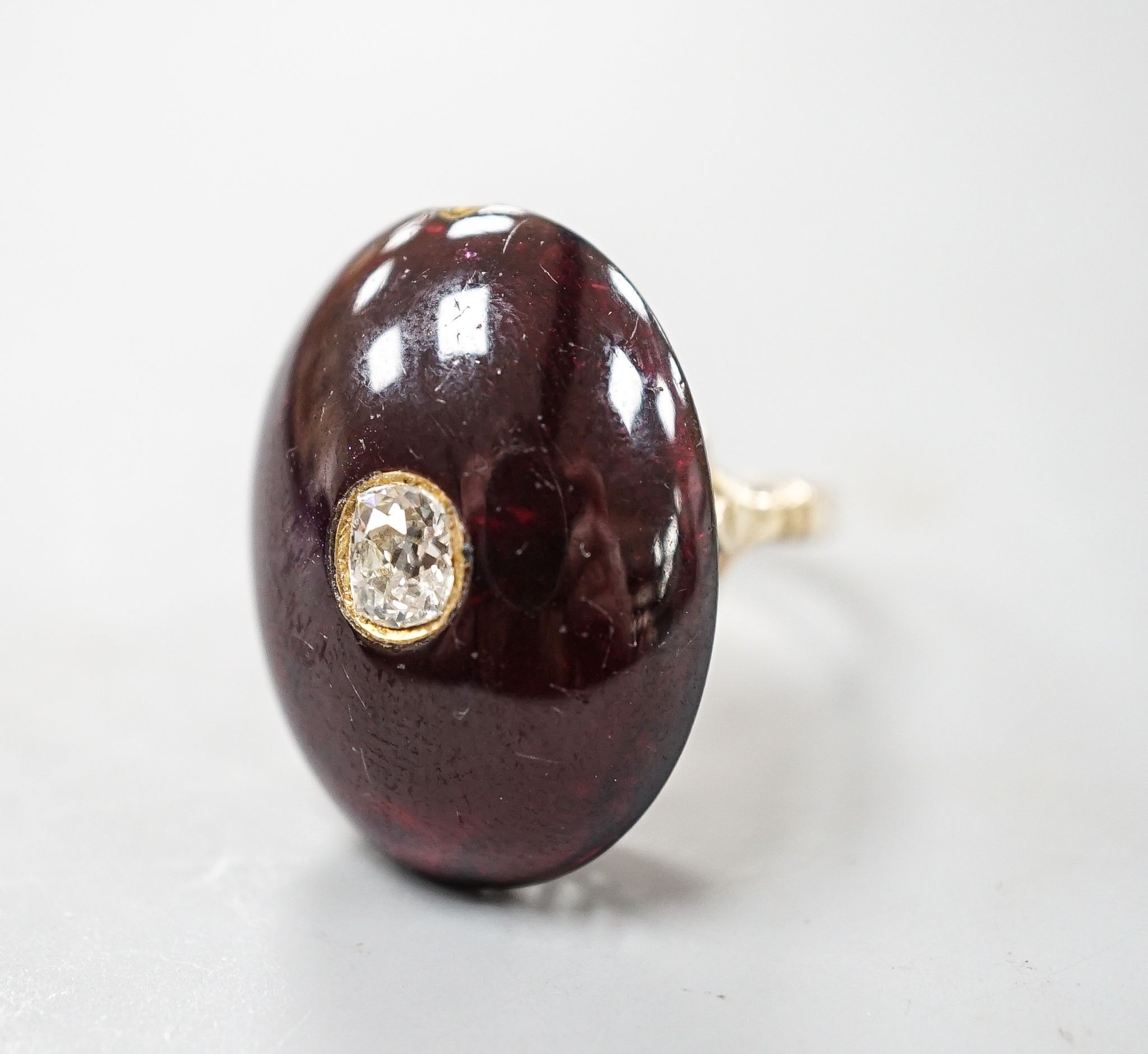 A yellow metal, foil backed cabochon garnet and diamond set oval dress ring, size P/Q, gross 11.1 grams, (a.f.).